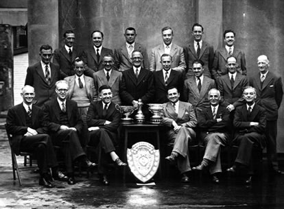 A group involved in the Civil Service Championships, Slade sitting to the right of the trophy table.